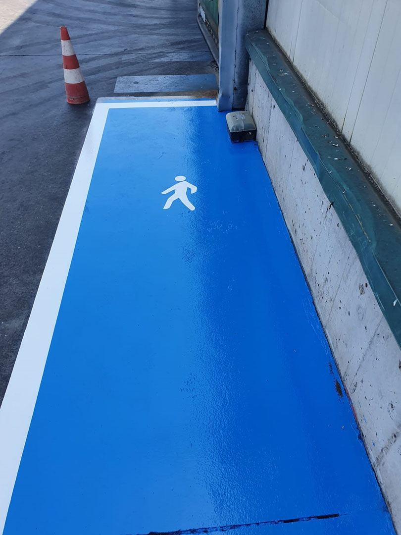Pasillo peatonal pintado en azul señal con pictograma